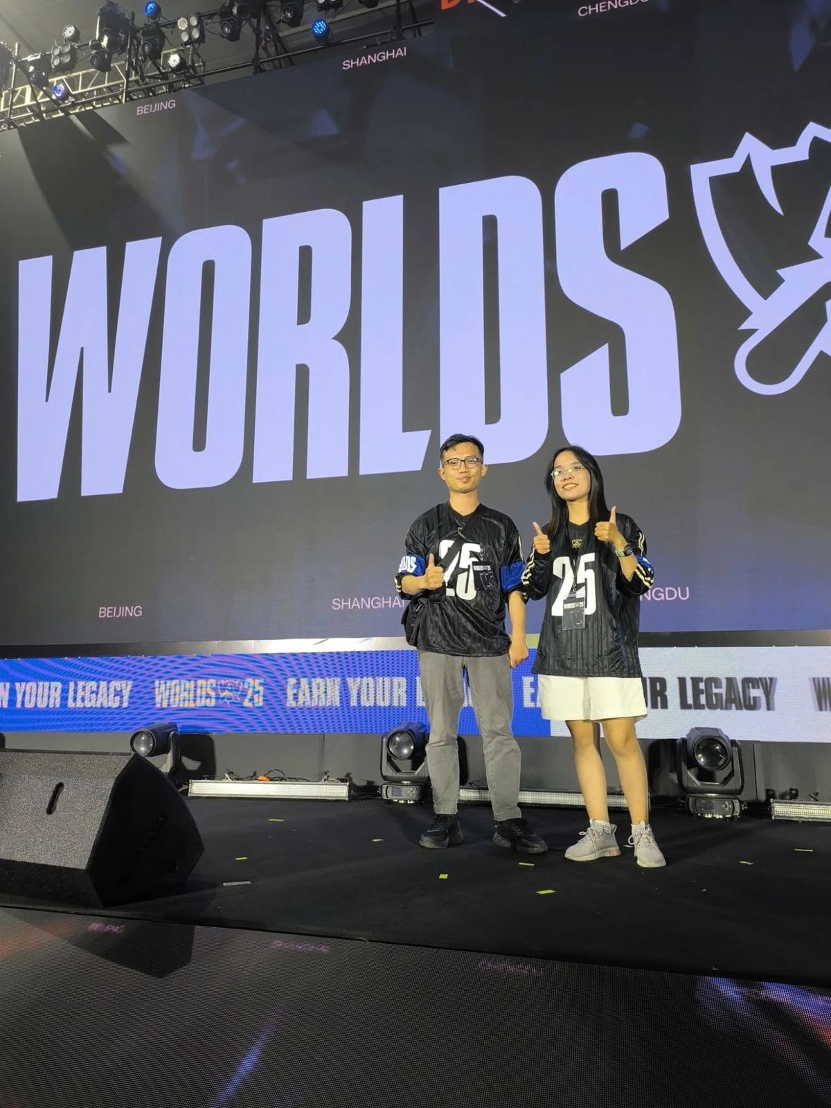 Tom cùng nhân sự phụ trách esport LMHT trên sân khấu Worlds 25, cả hai mặc áo đấu Worlds 25